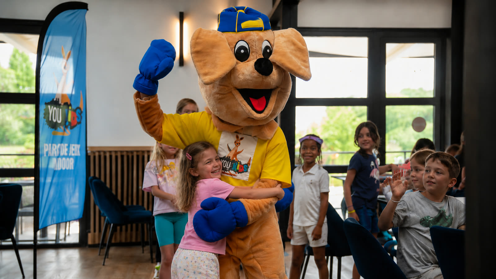 Enfant faisant un câlin à la mascotte You Kids pour clôturer son anniversaire
